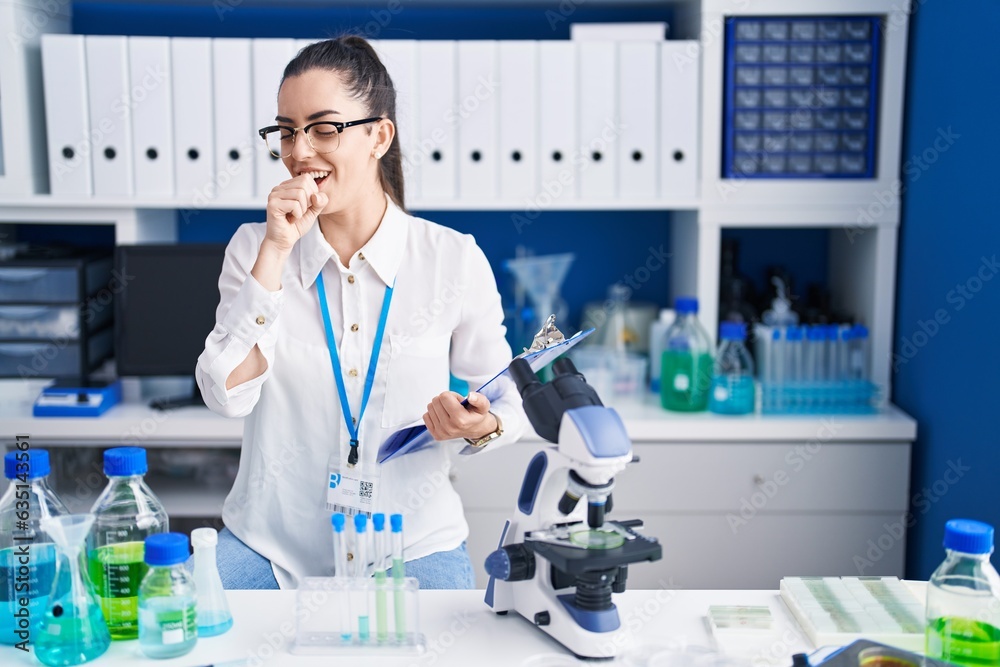 Poster young brunette woman working at scientist laboratory feeling unwell and coughing as symptom for cold