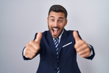 Handsome hispanic man wearing suit and tie approving doing positive gesture with hand, thumbs up...
