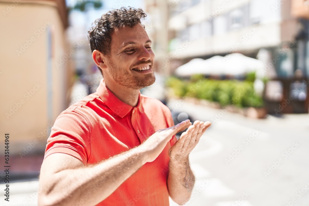 Wall mural young hispanic man smiling confident doing spend money gesture at street