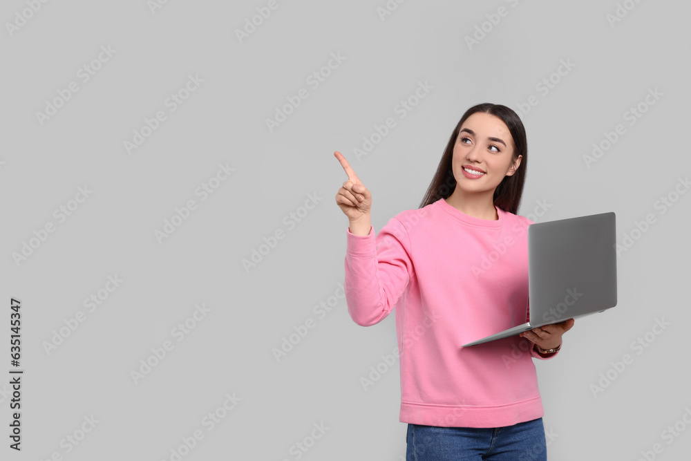 Sticker Smiling young woman with laptop on grey background, space for text