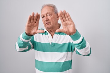 Senior man with grey hair standing over white background doing frame using hands palms and fingers, camera perspective