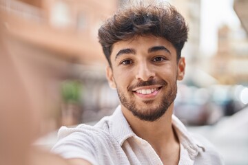 Young arab man smiling confident making selfie by the camera at street