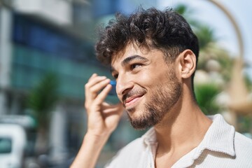 Young arab man smiling confident listening audio message by the smartphone at street