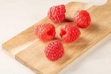 Fresh raspberries scattered on a bamboo cutting board
