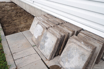 Facing concrete tiles lie on ground in stack. Replacing building foundation. Repair and construction. Background.