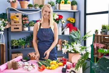 Young blonde woman florist make bouquet of flowers at florist store
