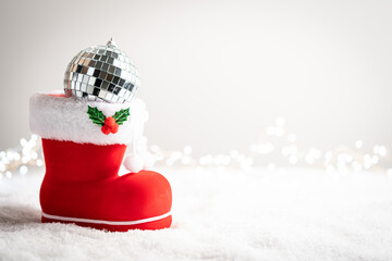 Christmas creative composition made with Santa boots with sweets and gifts on snow background. Minimal New Year shopping season concept. Winter holidays idea.