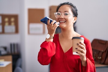 Fototapeta na wymiar Young chinese woman business worker talking on smartphone drinking coffee at office
