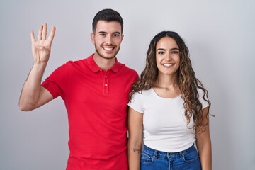 Young hispanic couple standing over isolated background showing and pointing up with fingers number...
