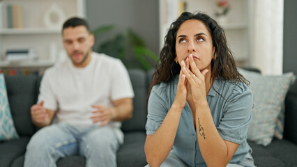 Man and woman couple sitting on sofa arguing stressed at home