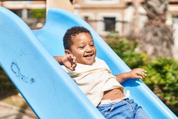 Fototapeta na wymiar African american child playing on slide at playground