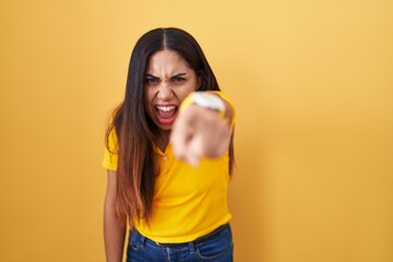 Young arab woman standing over yellow background pointing displeased and frustrated to the camera, angry and furious with you