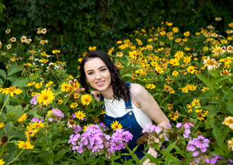 beautiful brunette smiling woman with yellow flowers in white t-shirt and blue denim overalls