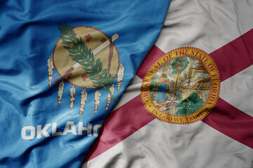 big waving colorful national flag of florida state and flag of oklahoma state .