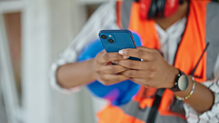 African american woman builder using smartphone at construction site