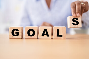 Black woman holding cubes with goals word on the table