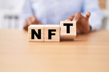 Black woman holding cubes with nft word on the table