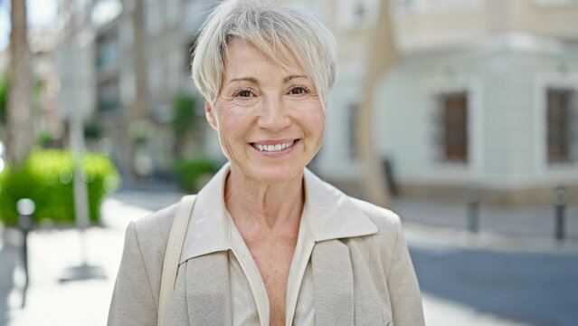Middle age blonde woman smiling confident standing at street
