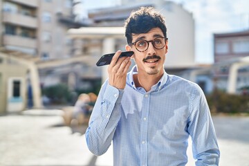 Young caucasian man smiling confident listening audio message by the smartphone at street