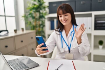 Young beautiful hispanic woman doctor smiling confident having video call at clinic