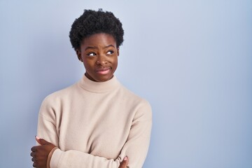 African american woman standing over blue background smiling looking to the side and staring away thinking.