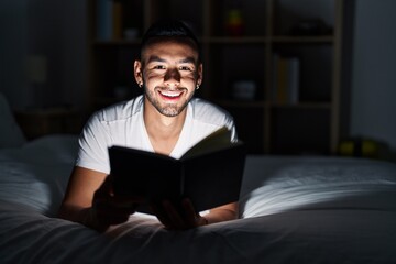 African american man reading book lying on bed at bedroom