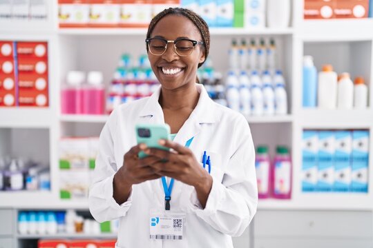 African american woman pharmacist using smartphone working at pharmacy