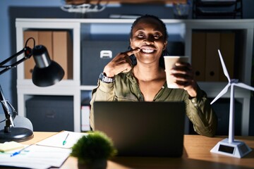 African woman working using computer laptop at night smiling cheerful showing and pointing with fingers teeth and mouth. dental health concept.