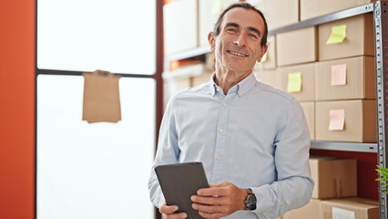 Middle age man ecommerce business worker using touchpad smiling at office