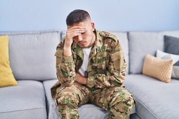 Young hispanic man army soldier sitting on sofa stressed at home