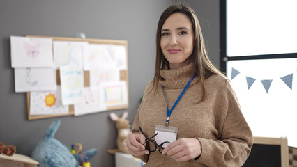Beautiful hispanic woman preschool teacher smiling confident standing at kindergarten