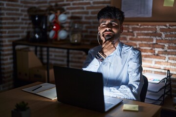 Plakat Young hispanic man with beard working at the office at night looking confident at the camera with smile with crossed arms and hand raised on chin. thinking positive.
