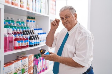 Middle age grey-haired man customer reading medication bottle label at pharmacy