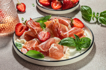 Slices of prosciutto di parma or jamon serrano iberico with strawberries, Antipasto Dinner or aperitivo party, place for text, top view