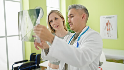 Obraz premium Man and woman doctor and patient having medical consultation looking xray at the clinic