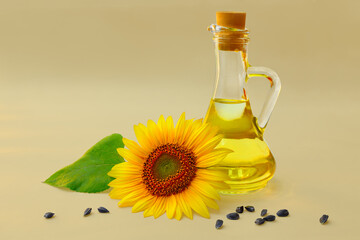 Sunflower oil in glass bottle with blooming sunflower and seeds on a warm background.