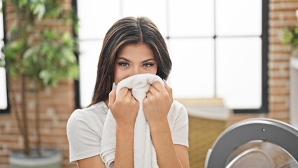 Young caucasian woman smelling clean towel at laundry room
