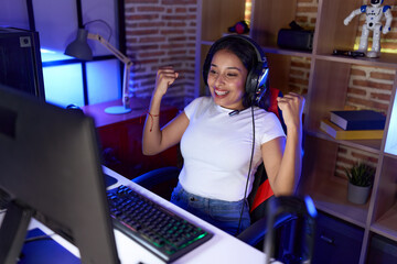 Young arab woman streamer playing video game with winner expression at gaming room © Krakenimages.com