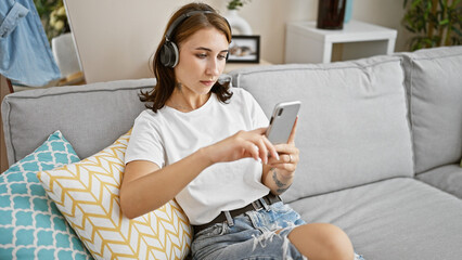 Young woman listening to music sitting on sofa at home