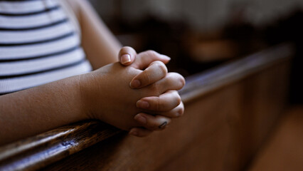 Young beautiful hispanic woman praying on a church bench at Augustinian Church in Vienna