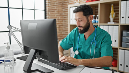 Young hispanic man doctor using computer working at the clinic