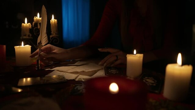 Close up shot of woman sitting on the table with many candles and tarot cards laying around.