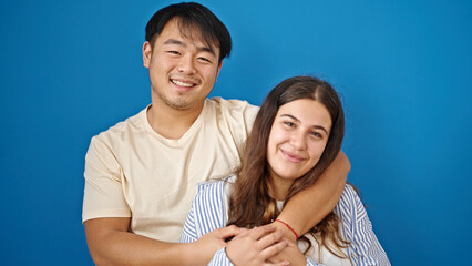 Man and woman couple smiling confident hugging each other over isolated blue background