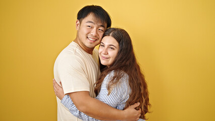 Fototapeta premium Man and woman couple smiling confident hugging each other over isolated yellow background