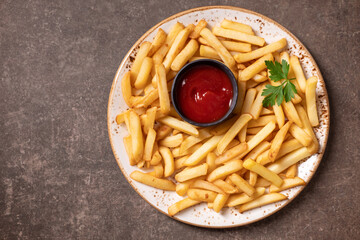 French fries and tomato ketchup on a rustic plate, top view