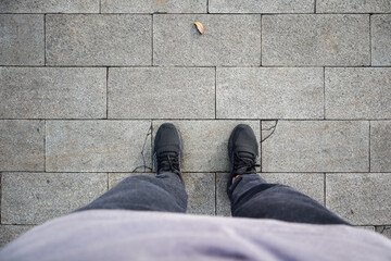 Men's feet wearing shoes stand on a paving stone road texture. Paving stones, paving background....