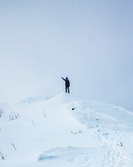 Naklejka na ściany i meble Hiker man standing and pointing on snowy mountain peak