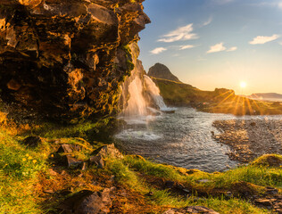 Fototapeta na wymiar Sunrise over volcanic Kirkjufell mountain with waterfall flowing in summer at Iceland