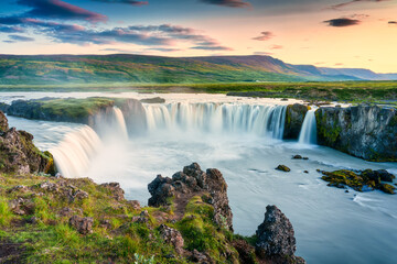 Godafoss waterfall flowing with colorful sunset sky in summer at Iceland