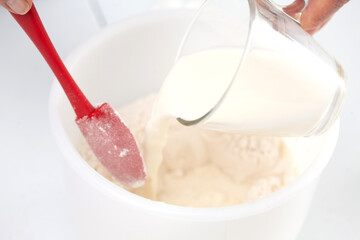 Home made pizza dough preparation. Adding milk. Pizza preparation.